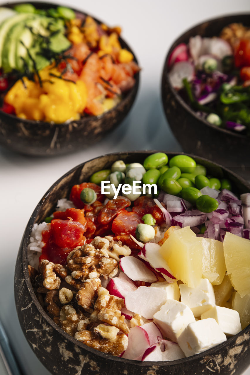Vertical image close up of poke bowl with fish, rice and fresh vegetables