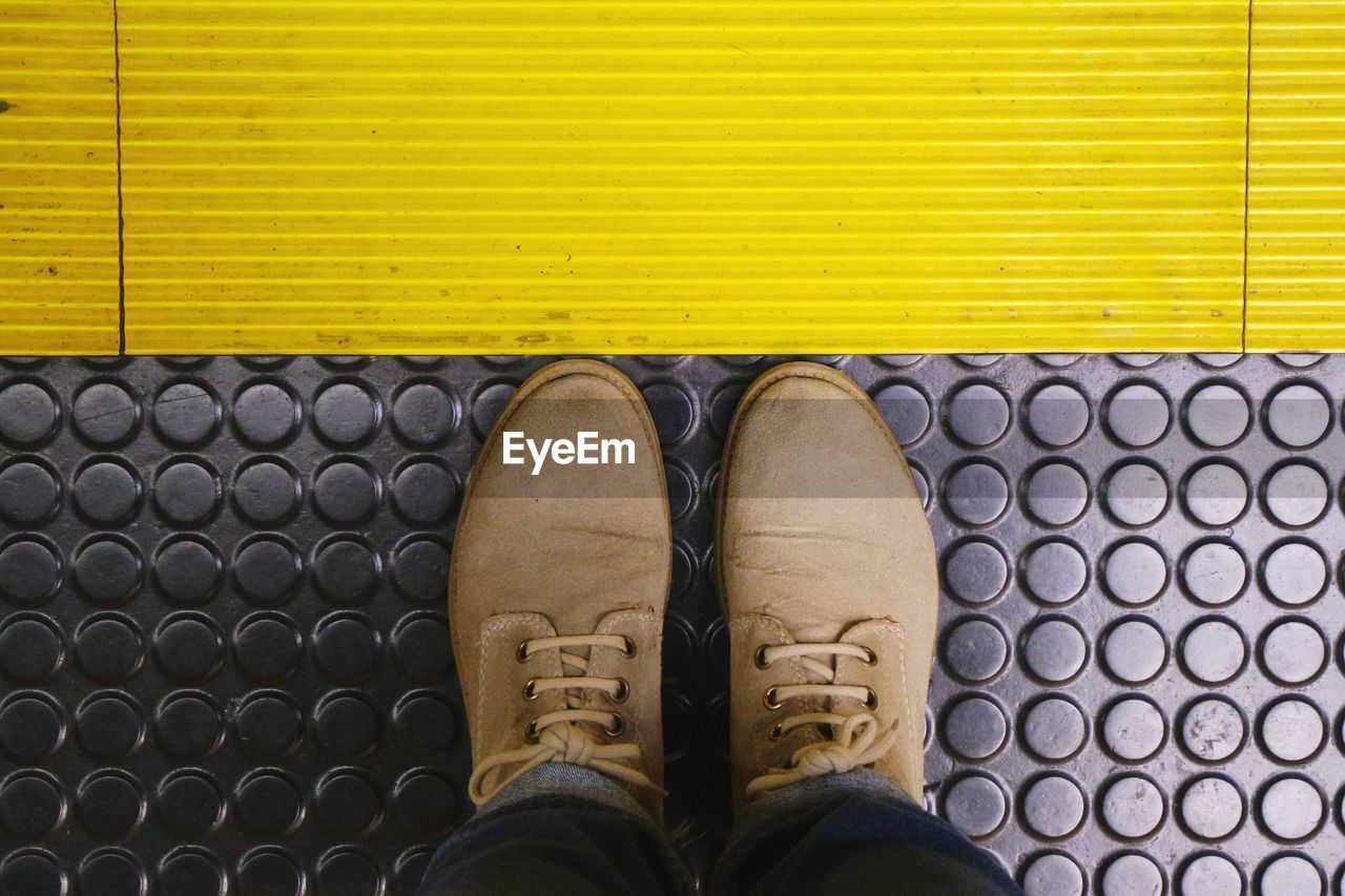 Low section of man standing on metallic floor