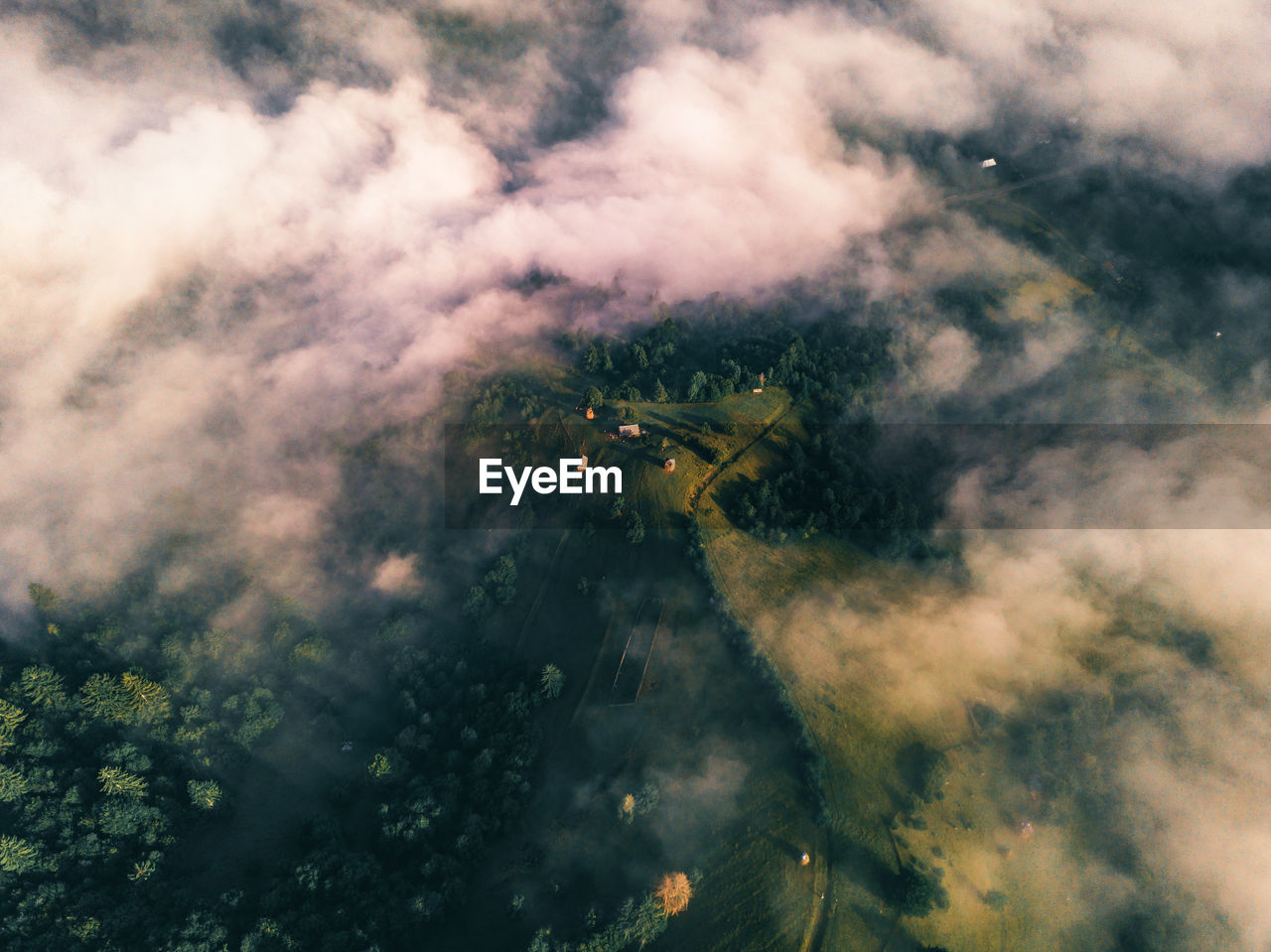 Aerial view of the small settlement surrounded by mountains. drone flight through the clouds 