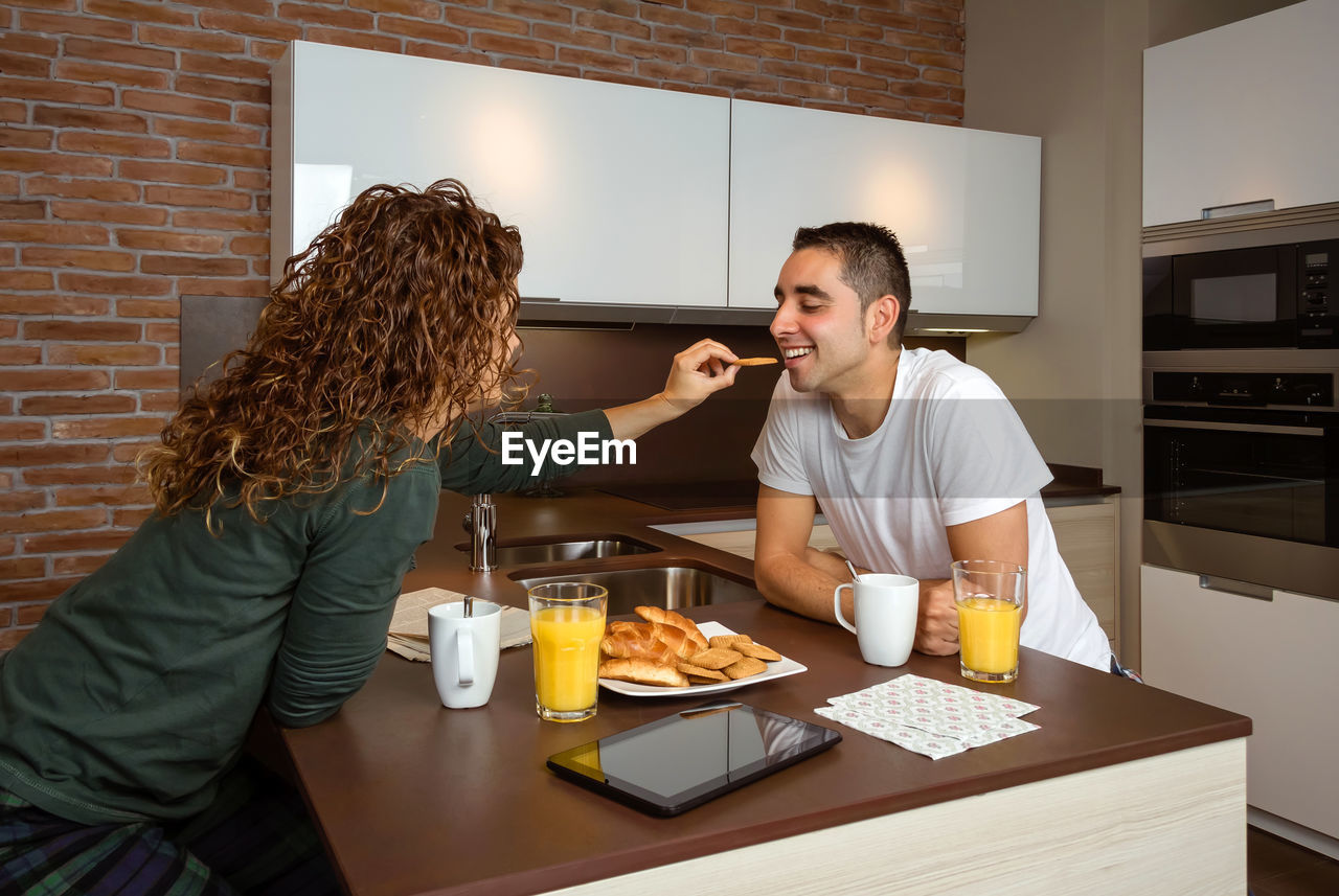 Wife giving cookie to husband at home