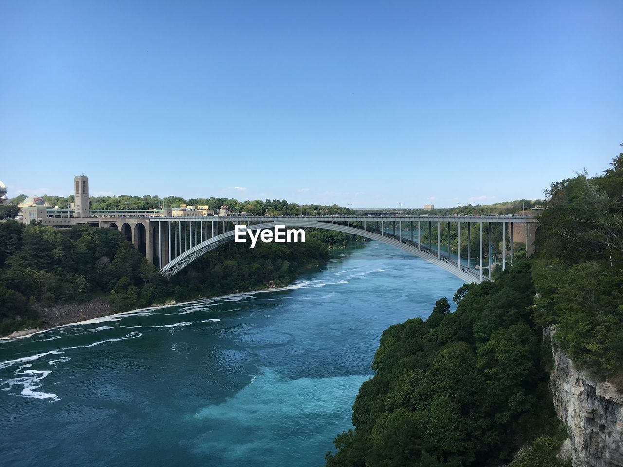 Bridge over river against clear blue sky