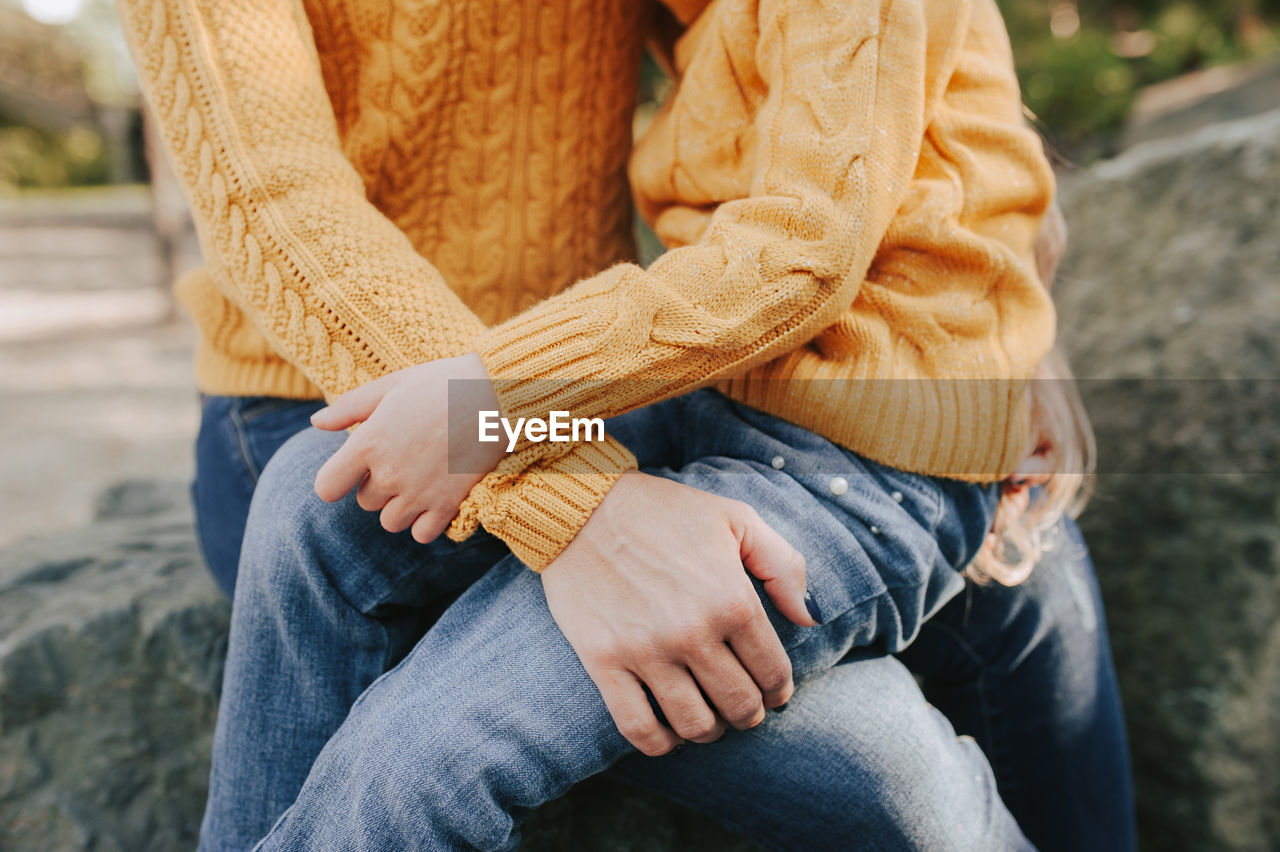 Gentle hug of parent and child dressed the same. warm autumn yellow sweater