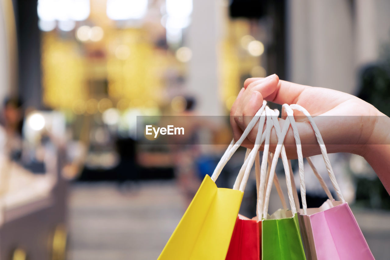 Cropped hand of woman holding paper bags in city