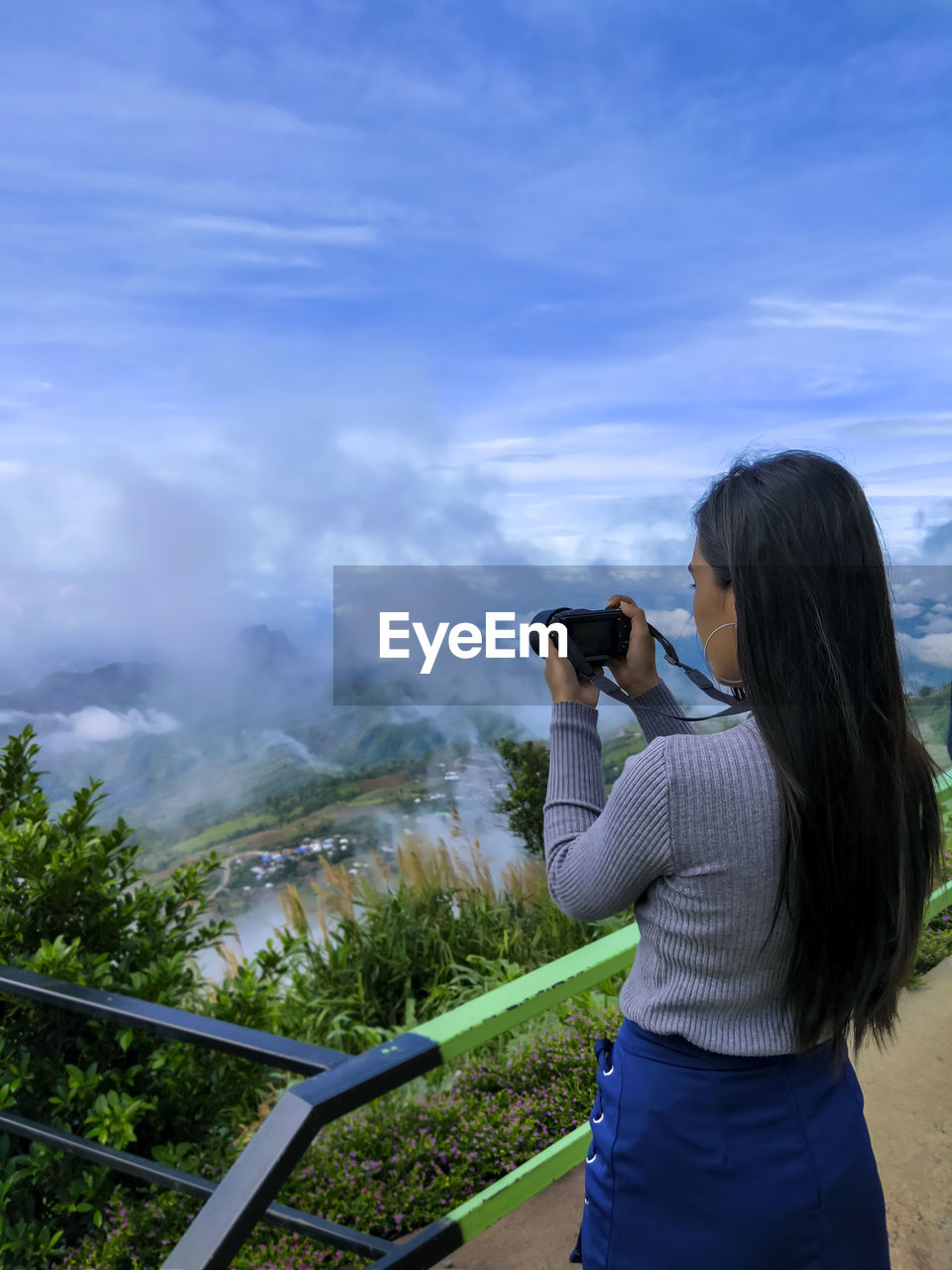 Rear view of woman photographing against sky