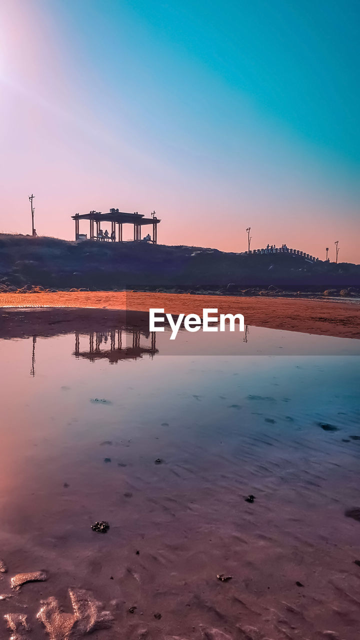 SCENIC VIEW OF BEACH AGAINST SKY AT SUNSET