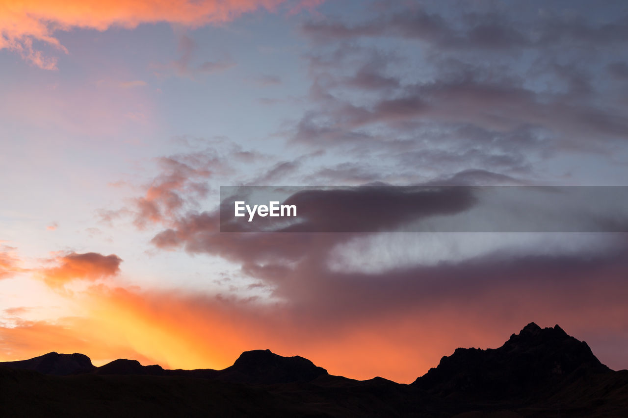 LOW ANGLE VIEW OF SILHOUETTE MOUNTAINS AGAINST ORANGE SKY