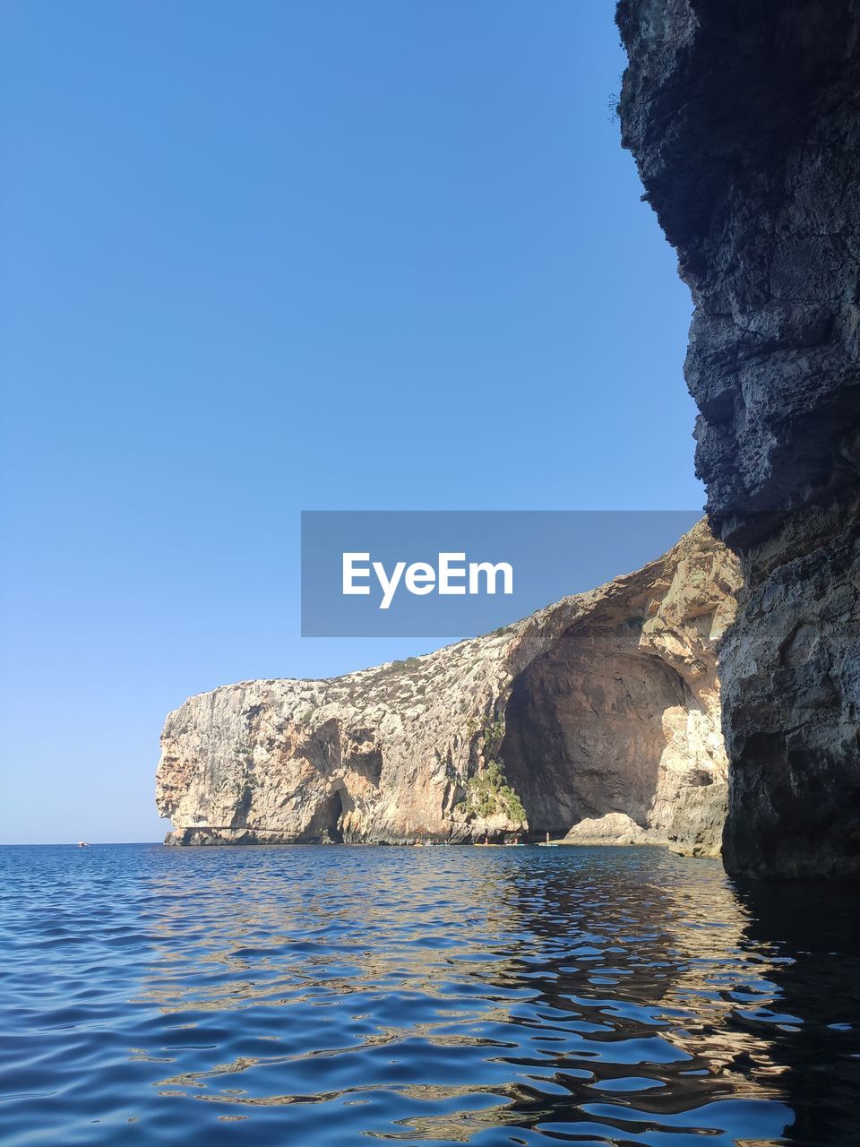 blue, reflection, cave, nature, sky, no people, clear sky, day, water, rock, formation, outdoors, architecture, low angle view, ice, terrain, sunlight, beauty in nature, rock formation, sunny