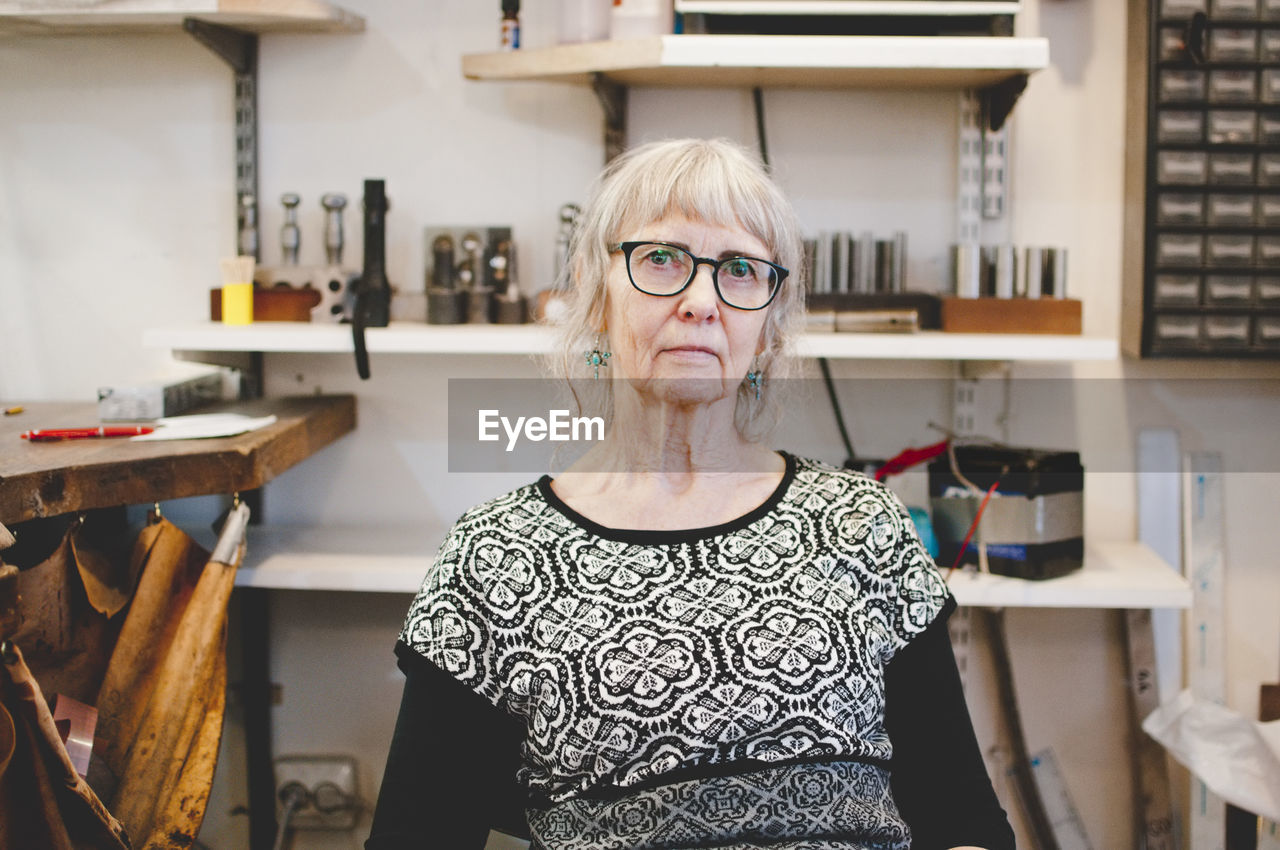 Portrait of confident senior female owner in jewelry workshop
