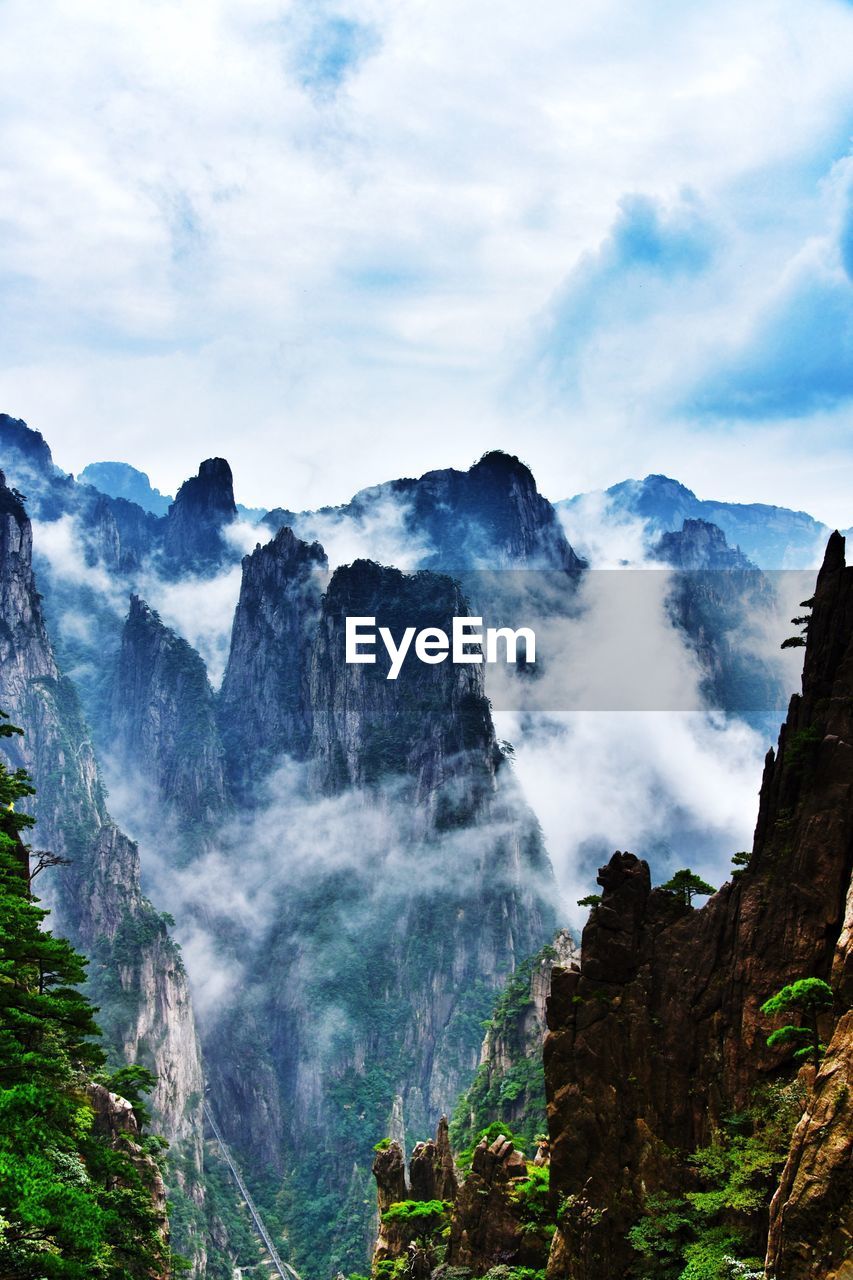 Scenic view of waterfall against cloudy sky