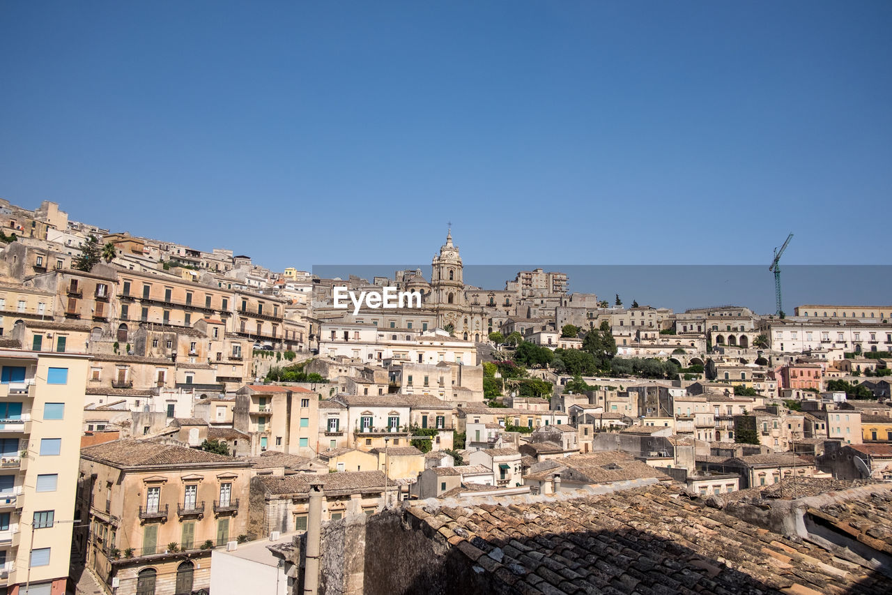 Buildings in city against clear blue sky