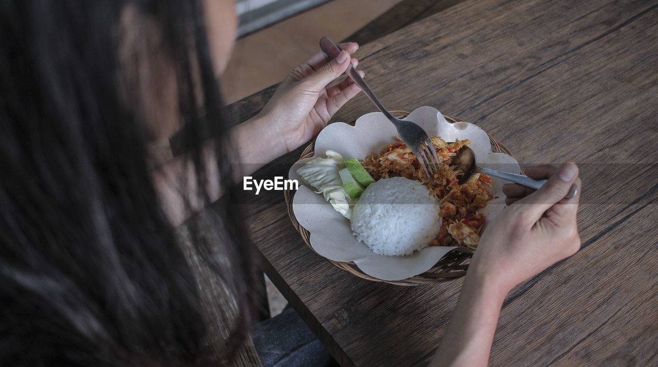 High angle view of woman holding food on table