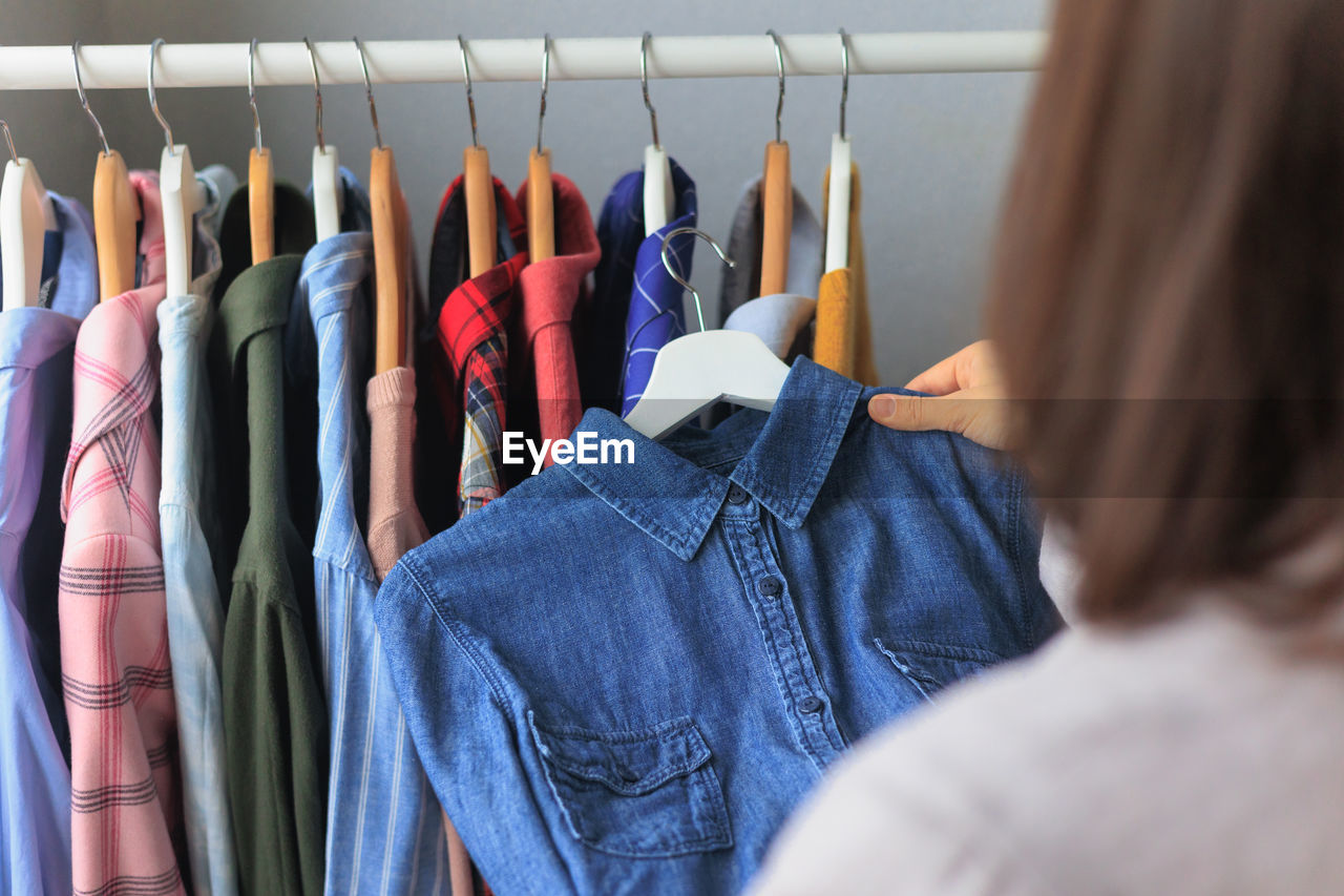 rear view of woman with clothes hanging on rack