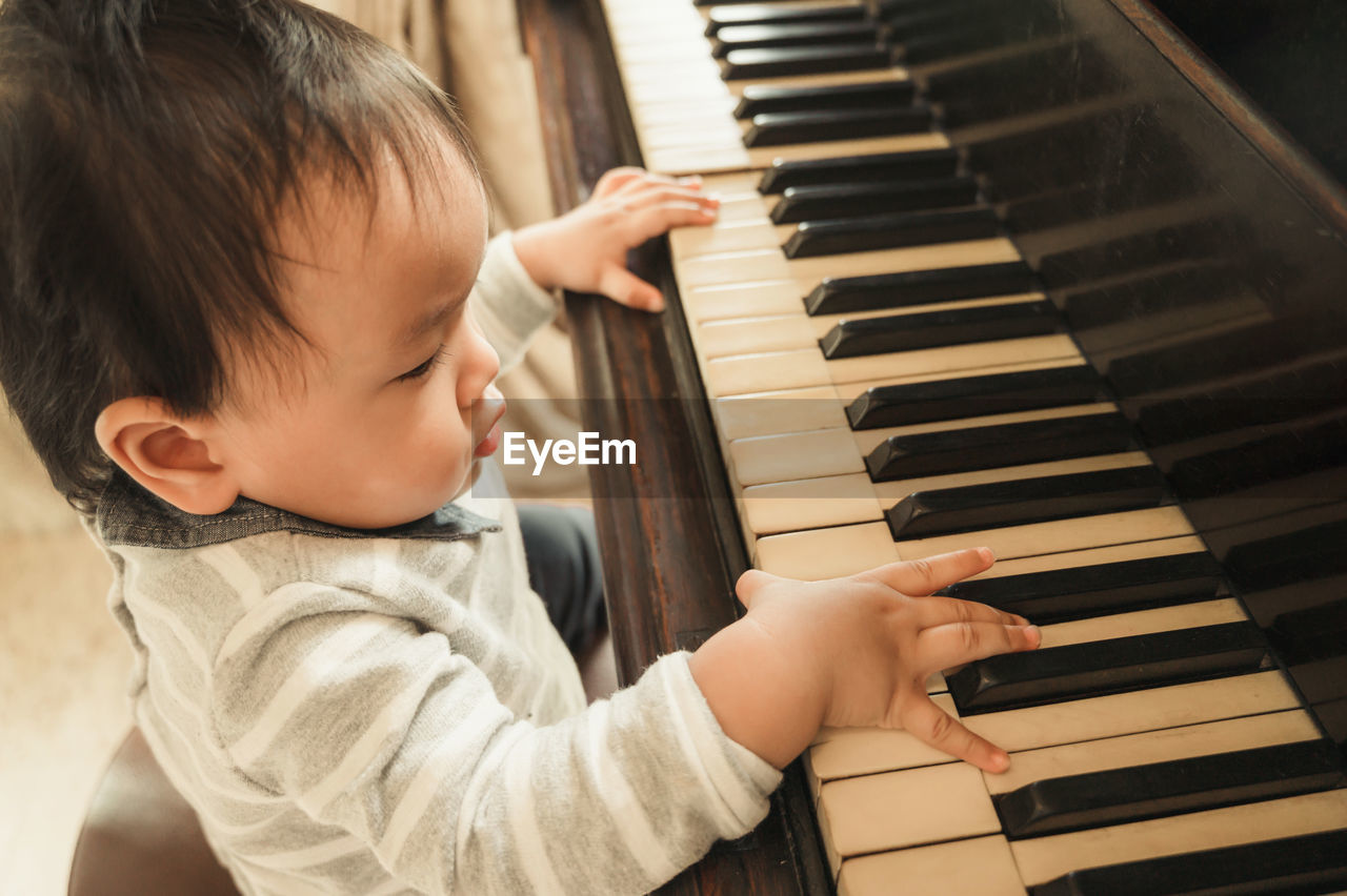 Cute boy playing piano at home