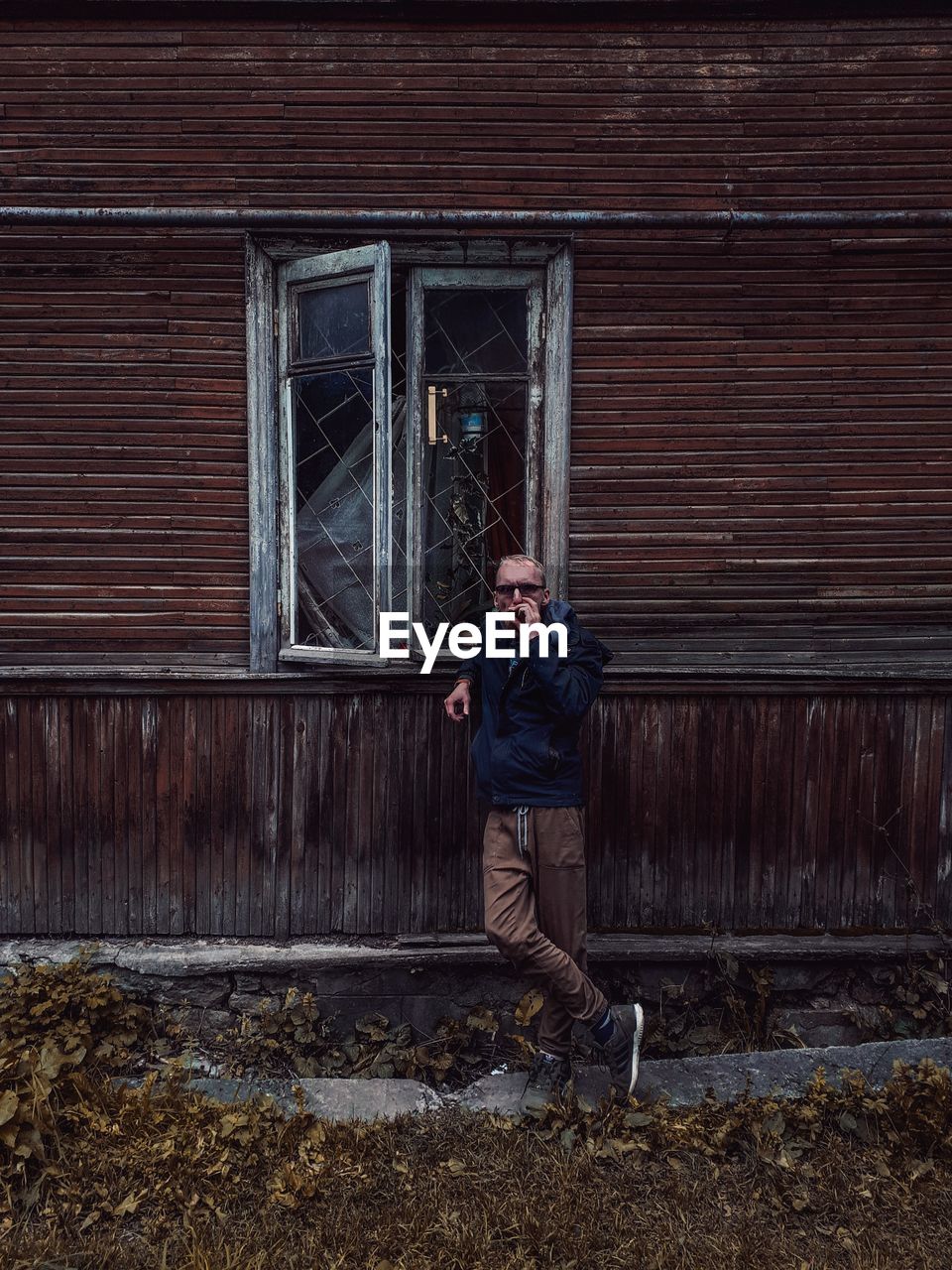 MAN STANDING BY HOUSE AGAINST BUILDING