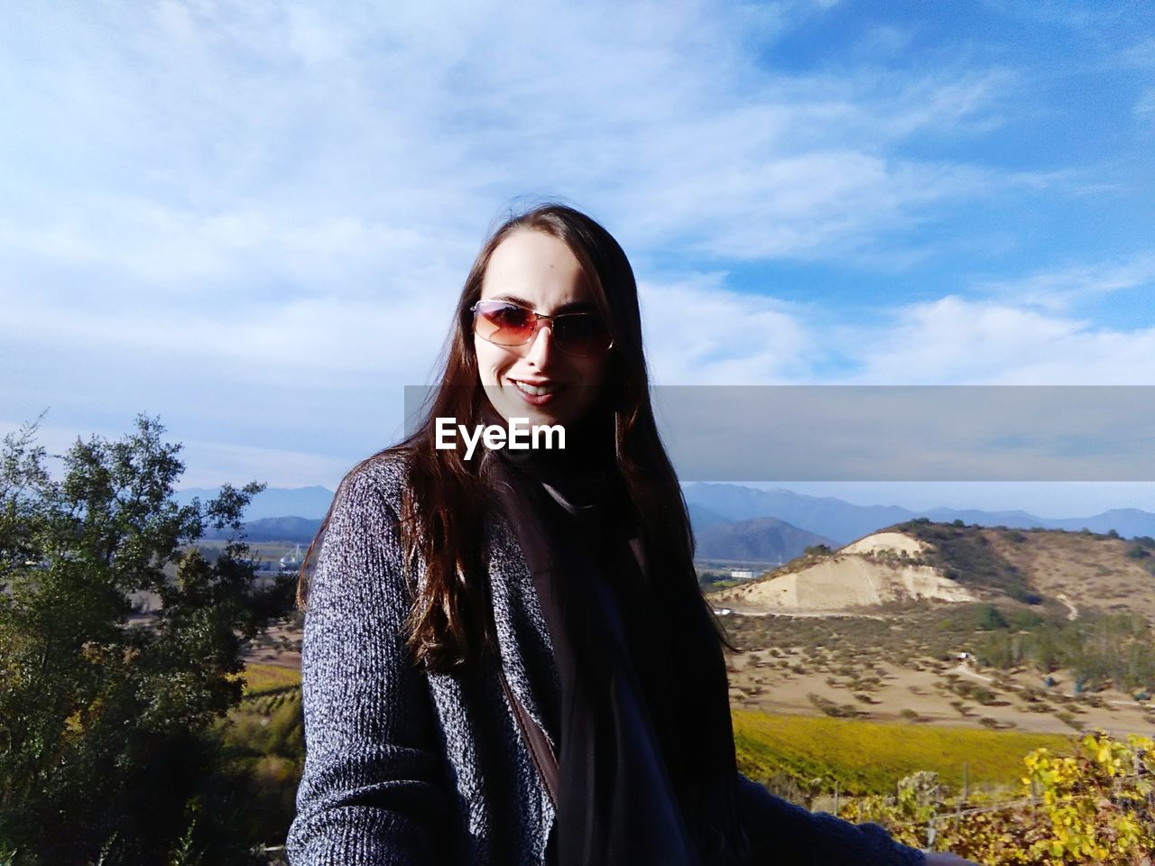 Portrait of smiling young woman against landscape