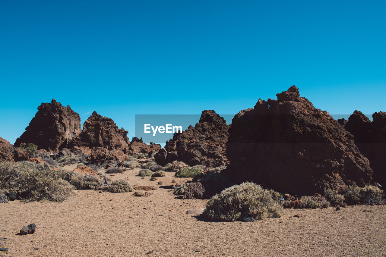 Rock formations on landscape against clear blue sky