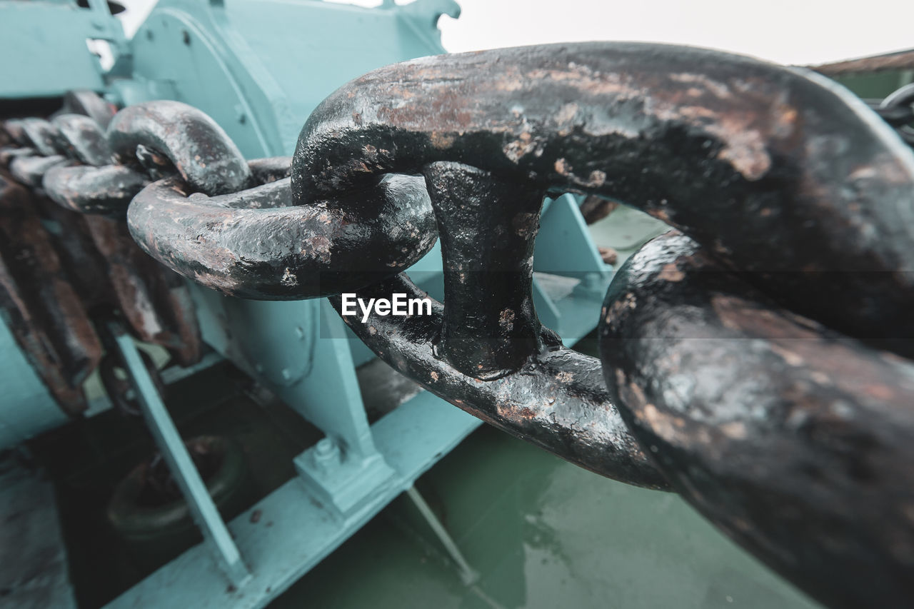 CLOSE-UP OF RUSTY CHAIN ON METAL