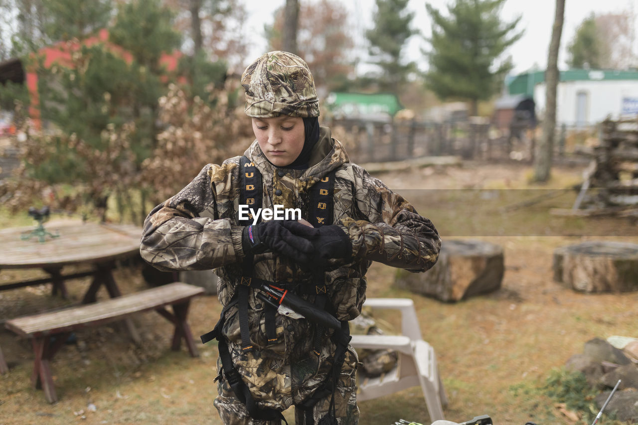 Boy wearing camouflage clothing while standing on field