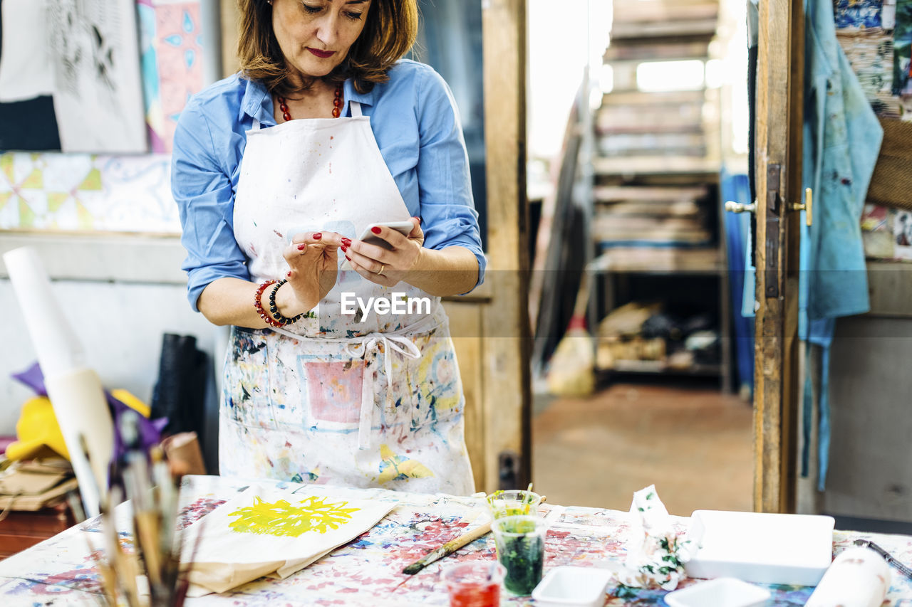 Female artist checking phone in workshop