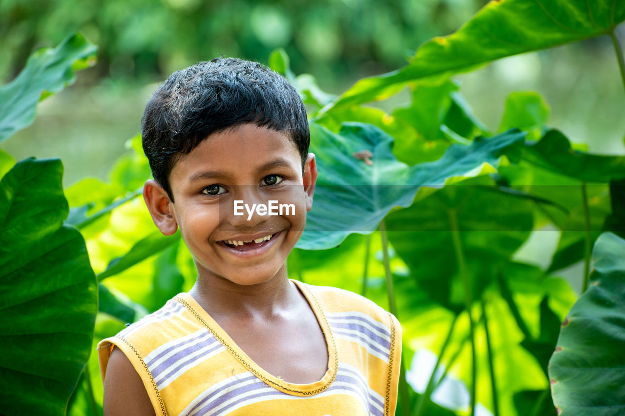 The portrait of a beautiful serene indian child in the background of a dark green forest
