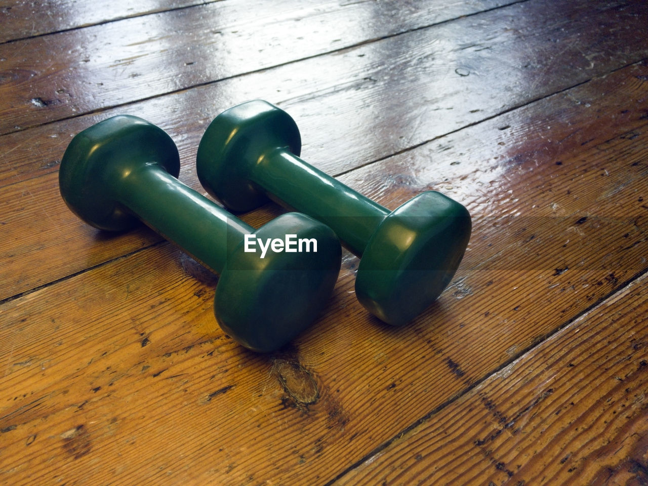 Close-up of green dumbbells on wooden table