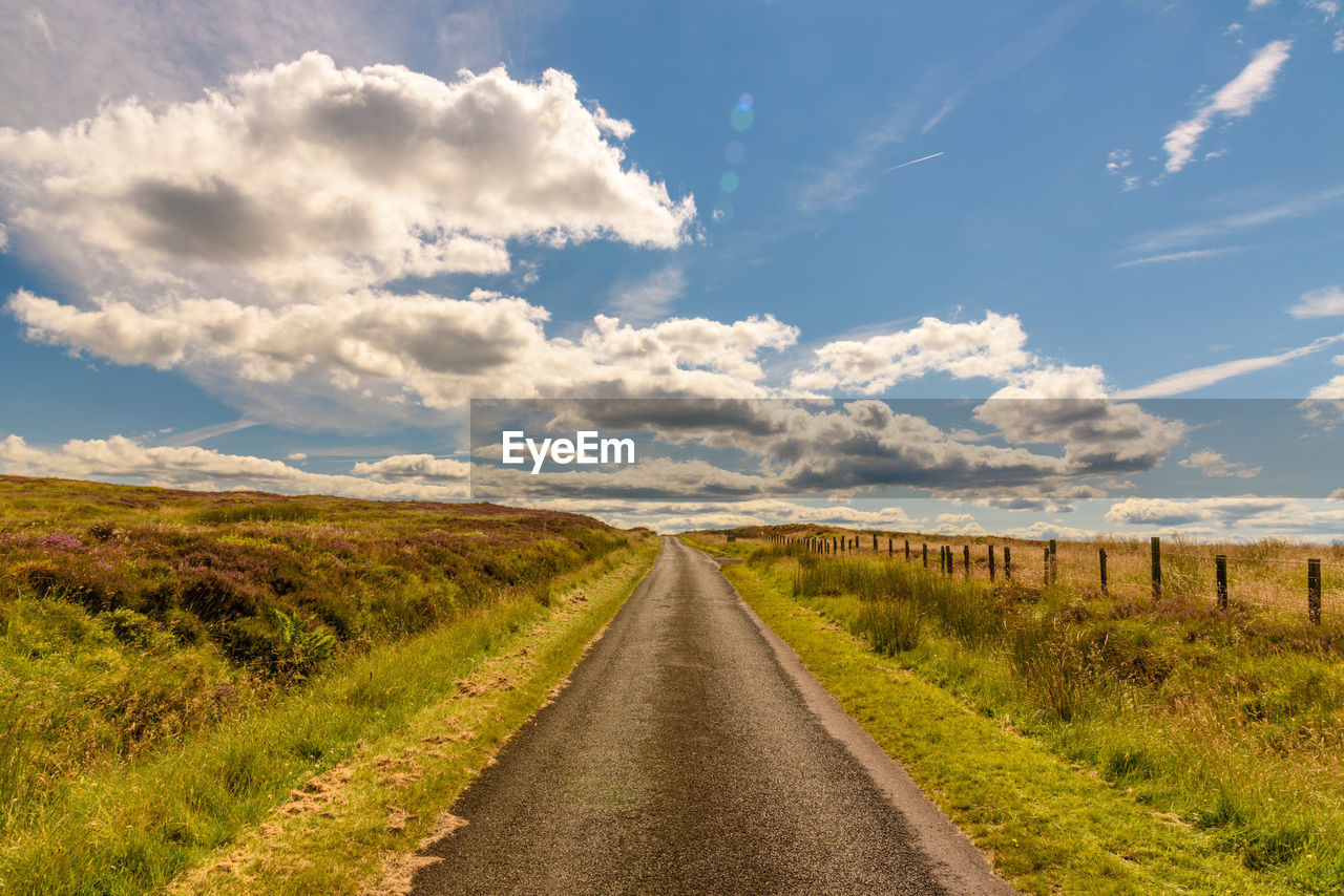 Road amidst field against sky