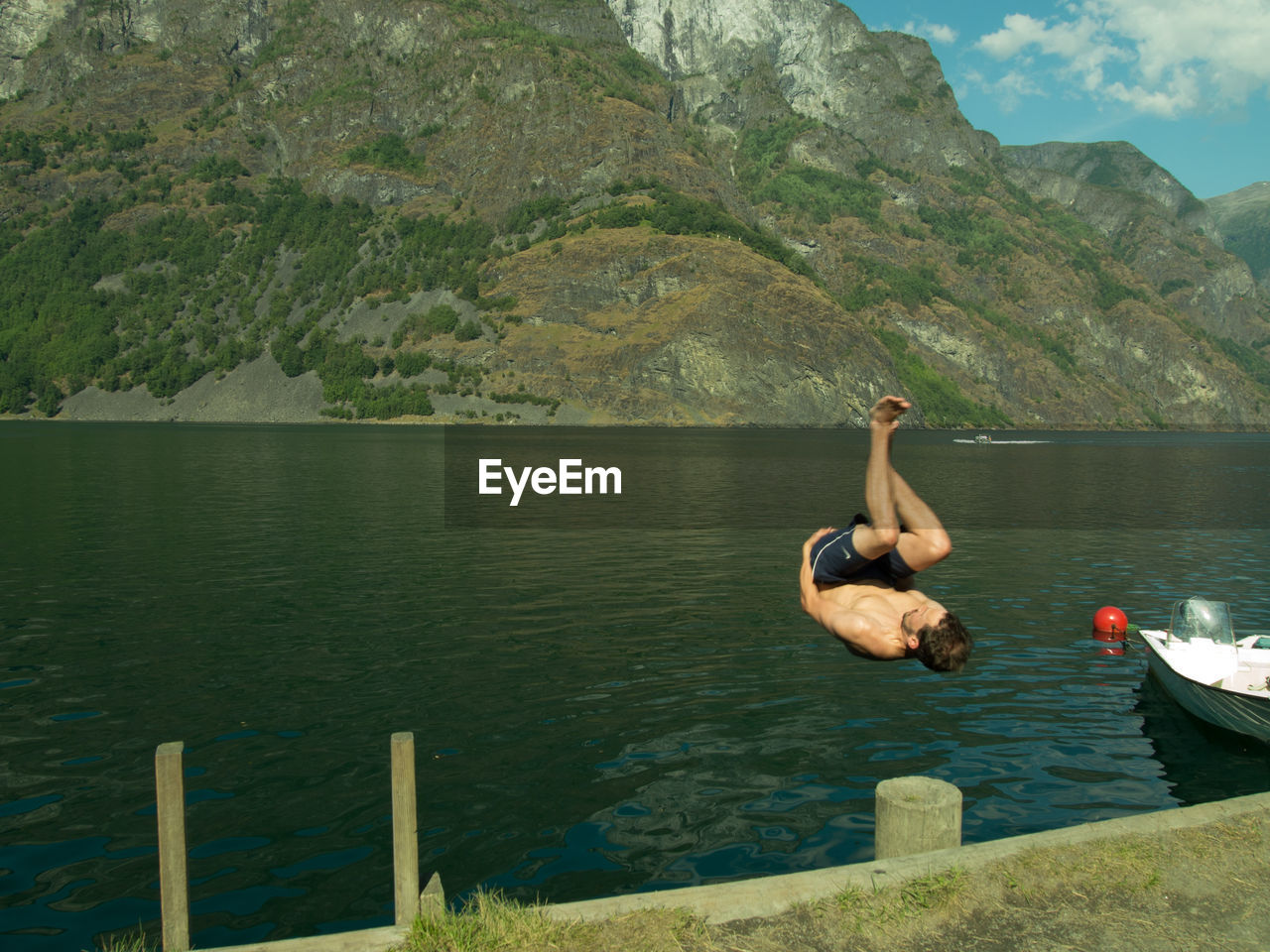 Shirtless man diving in lake by mountain