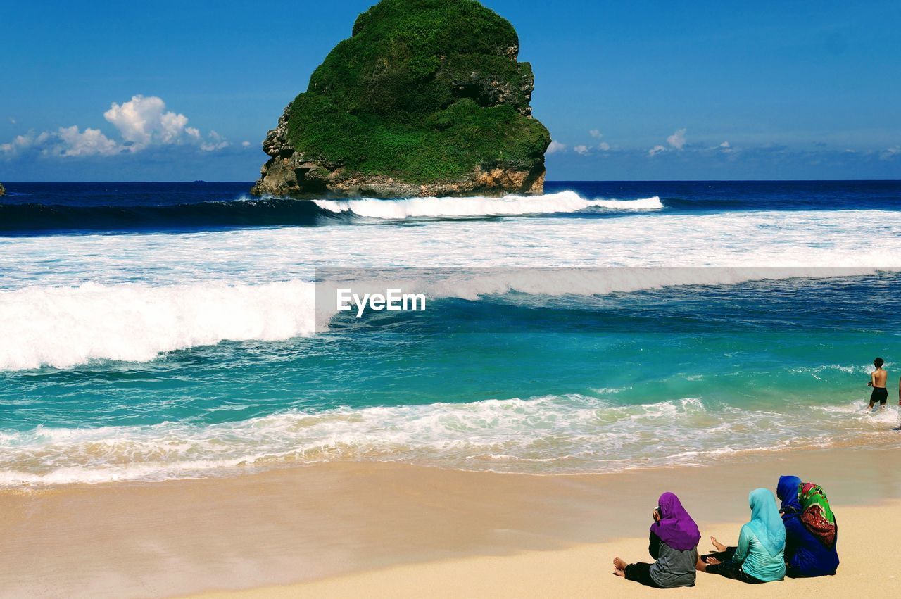 People at beach against sky
