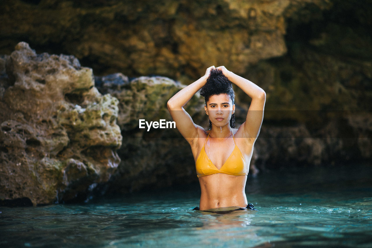 Portrait of sensuous woman wearing bikini while standing in sea
