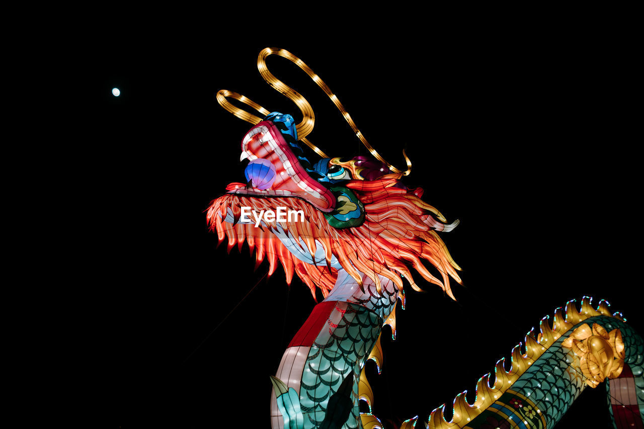 LOW ANGLE VIEW OF ILLUMINATED DECORATION OVER BLACK BACKGROUND