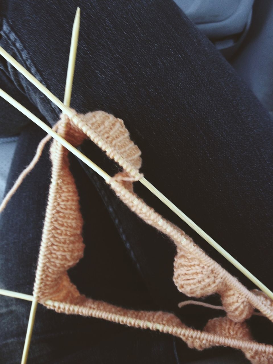 Close-up of wool and knitting needles on female lap