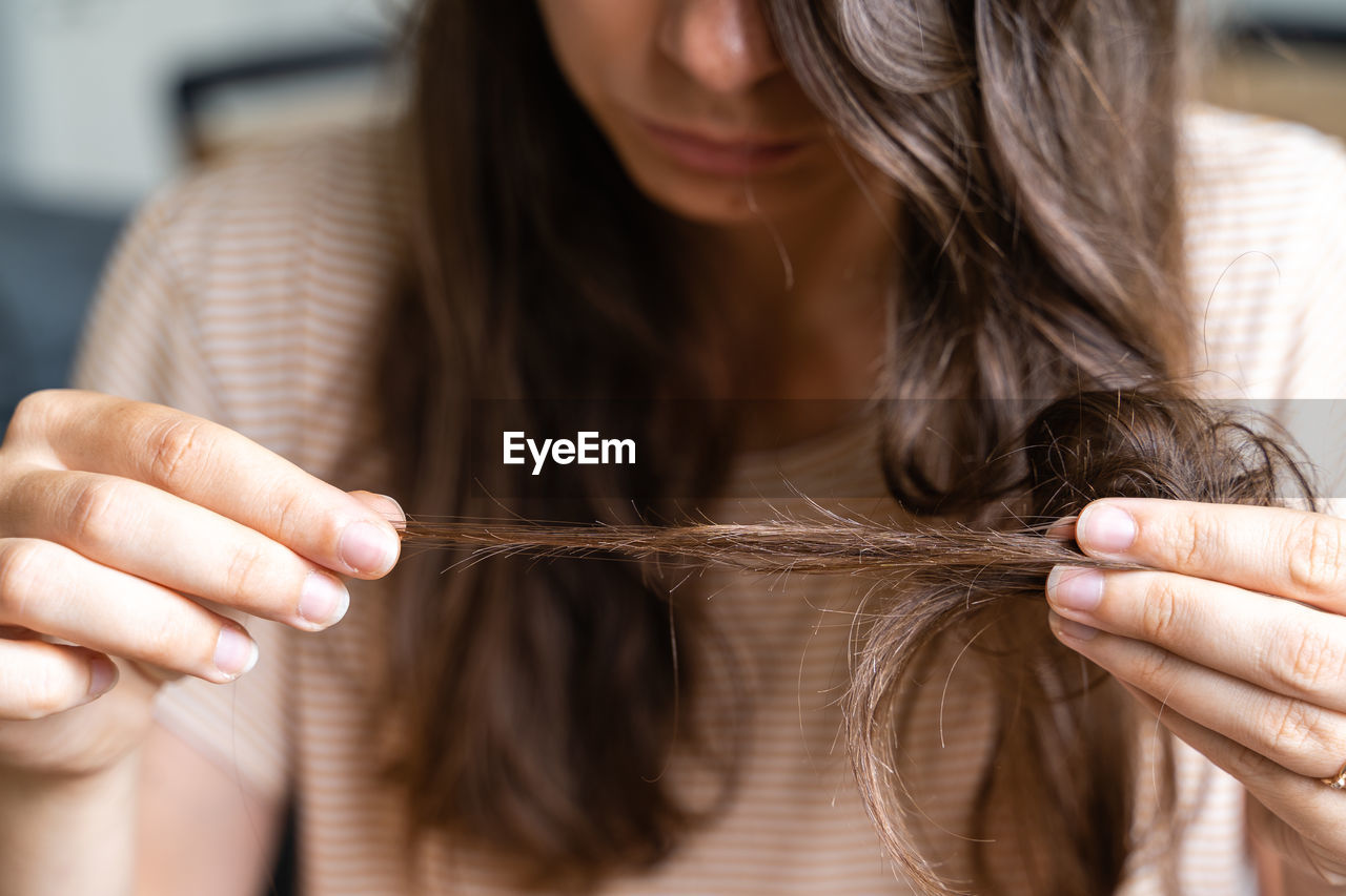 MIDSECTION OF WOMAN HOLDING HANDS WITH HAIR