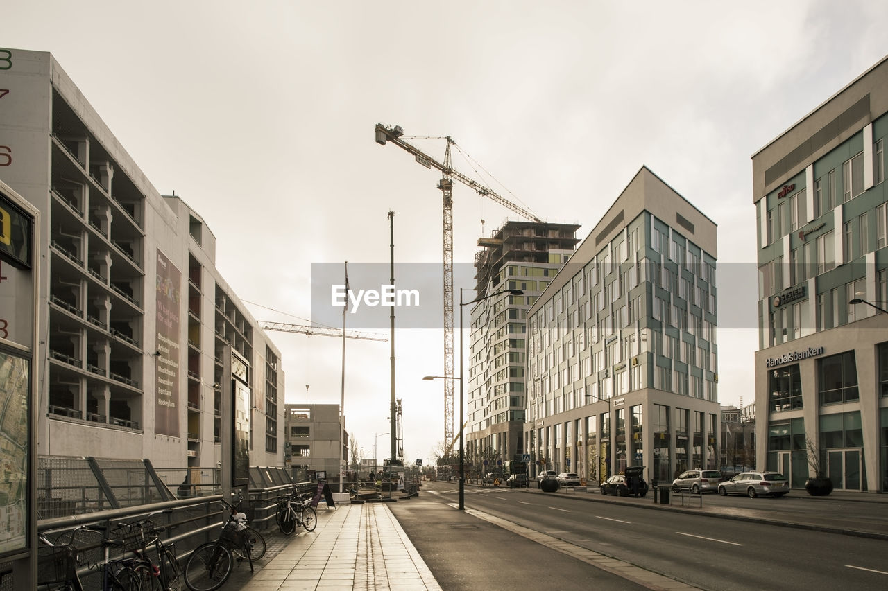 City street and buildings with crane against sky