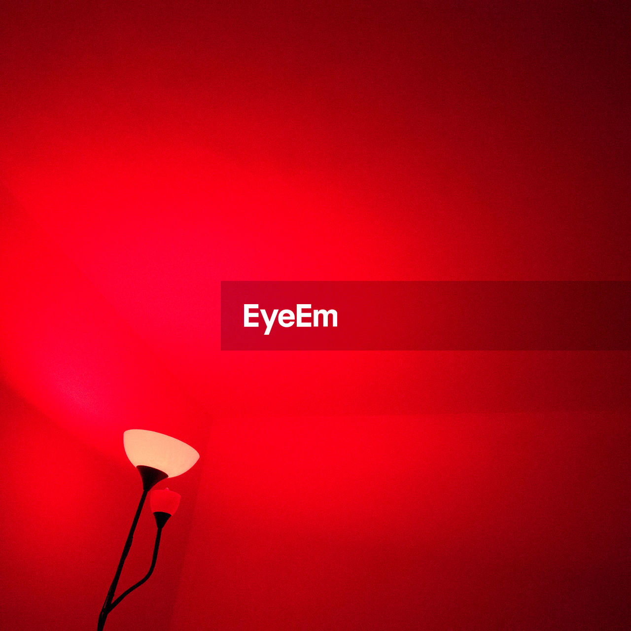 Cropped image of illuminated lamp against red wall at home