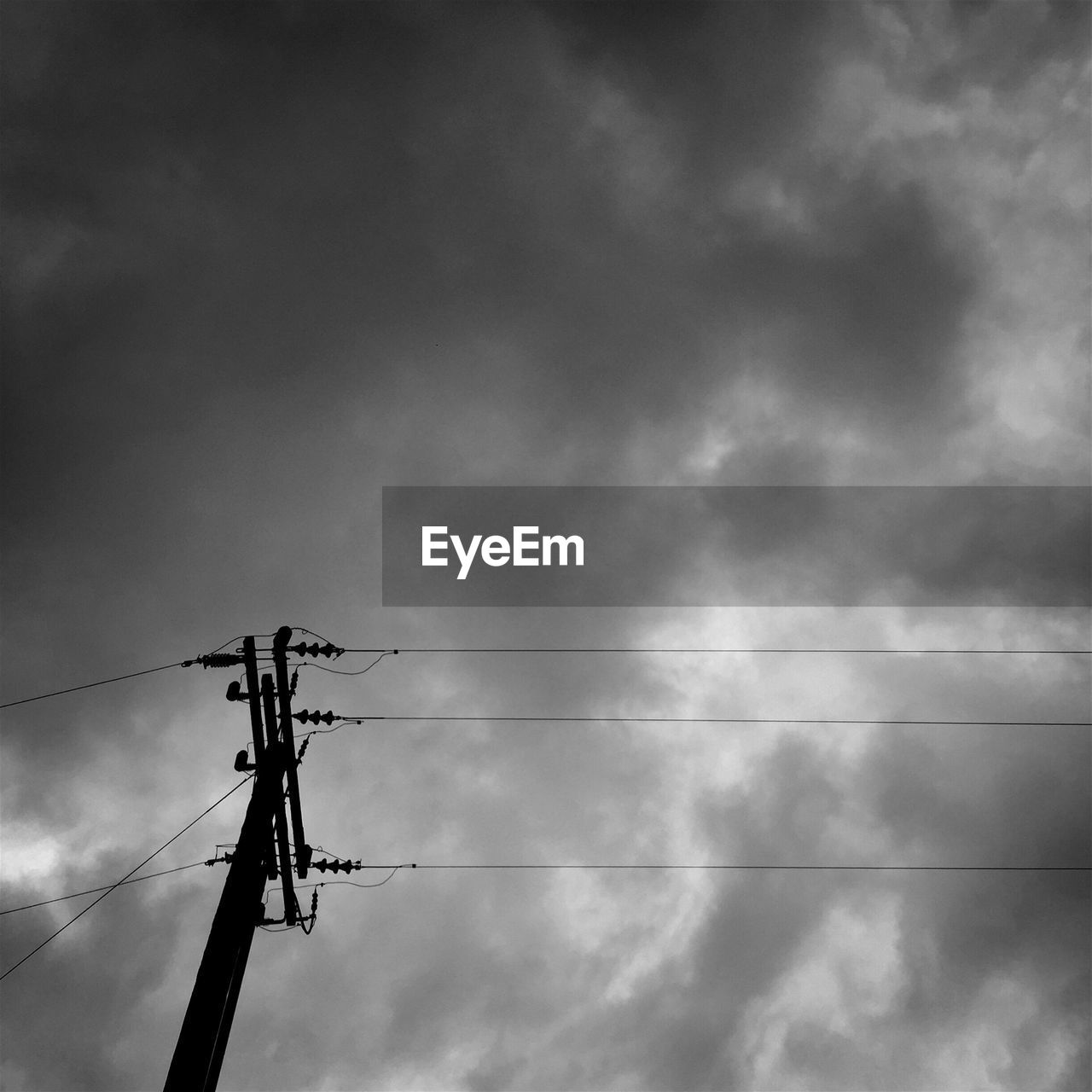 Low angle view of electric pylon against cloudy sky