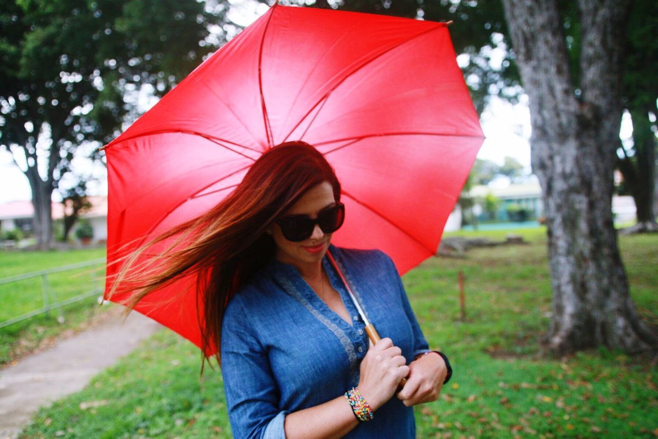 PORTRAIT OF YOUNG WOMAN HOLDING RED UMBRELLA