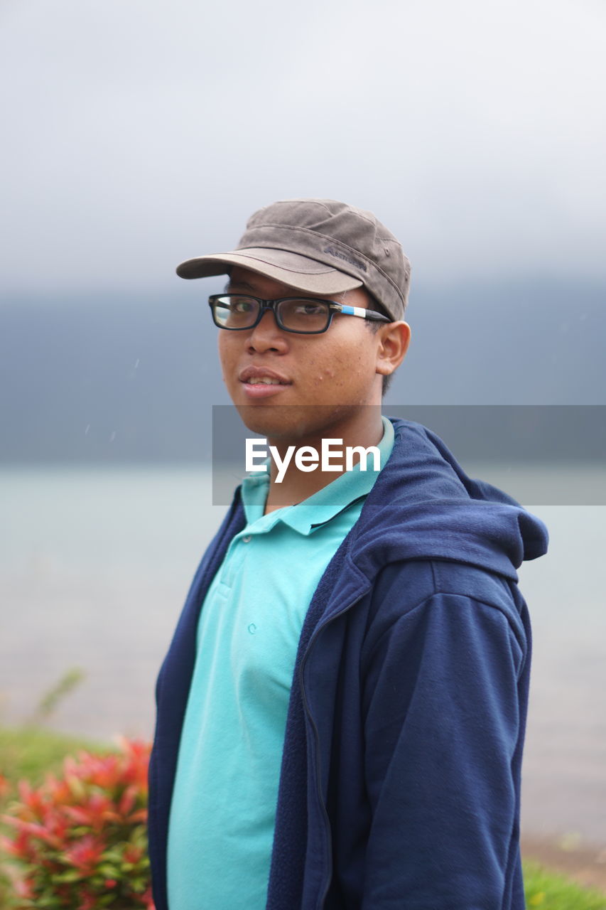 Portrait of smiling young man standing against sky