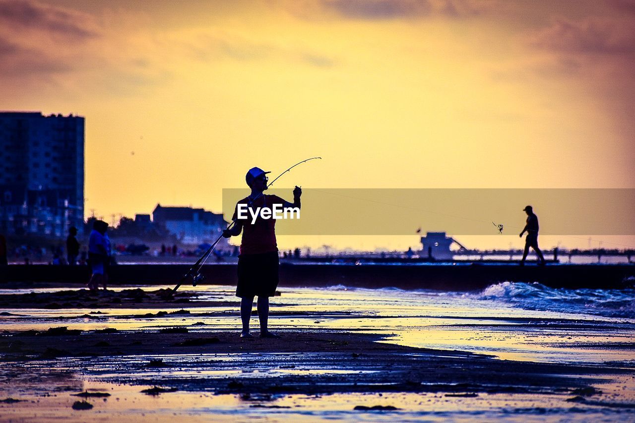 SILHOUETTE PEOPLE ON BEACH AGAINST SKY DURING SUNSET