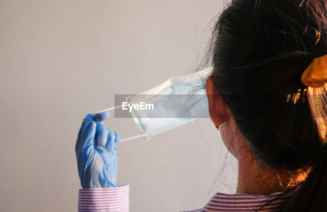 Rear view of woman holding face mask against corona virus