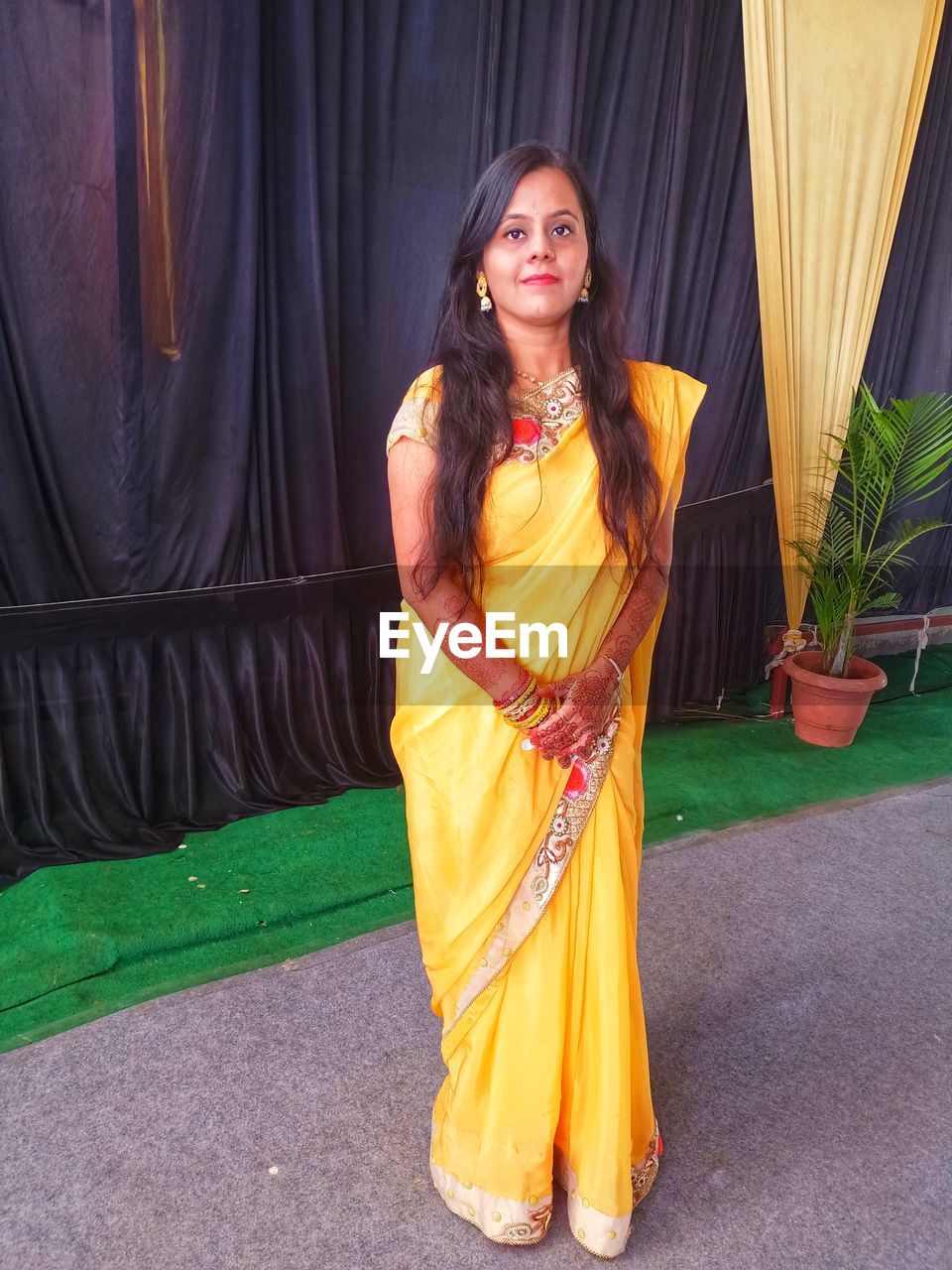 yellow, one person, clothing, adult, women, portrait, young adult, smiling, full length, looking at camera, traditional clothing, fashion, dress, standing, arts culture and entertainment, front view, happiness, curtain, long hair, sari, lifestyles, hairstyle, architecture, emotion, brown hair