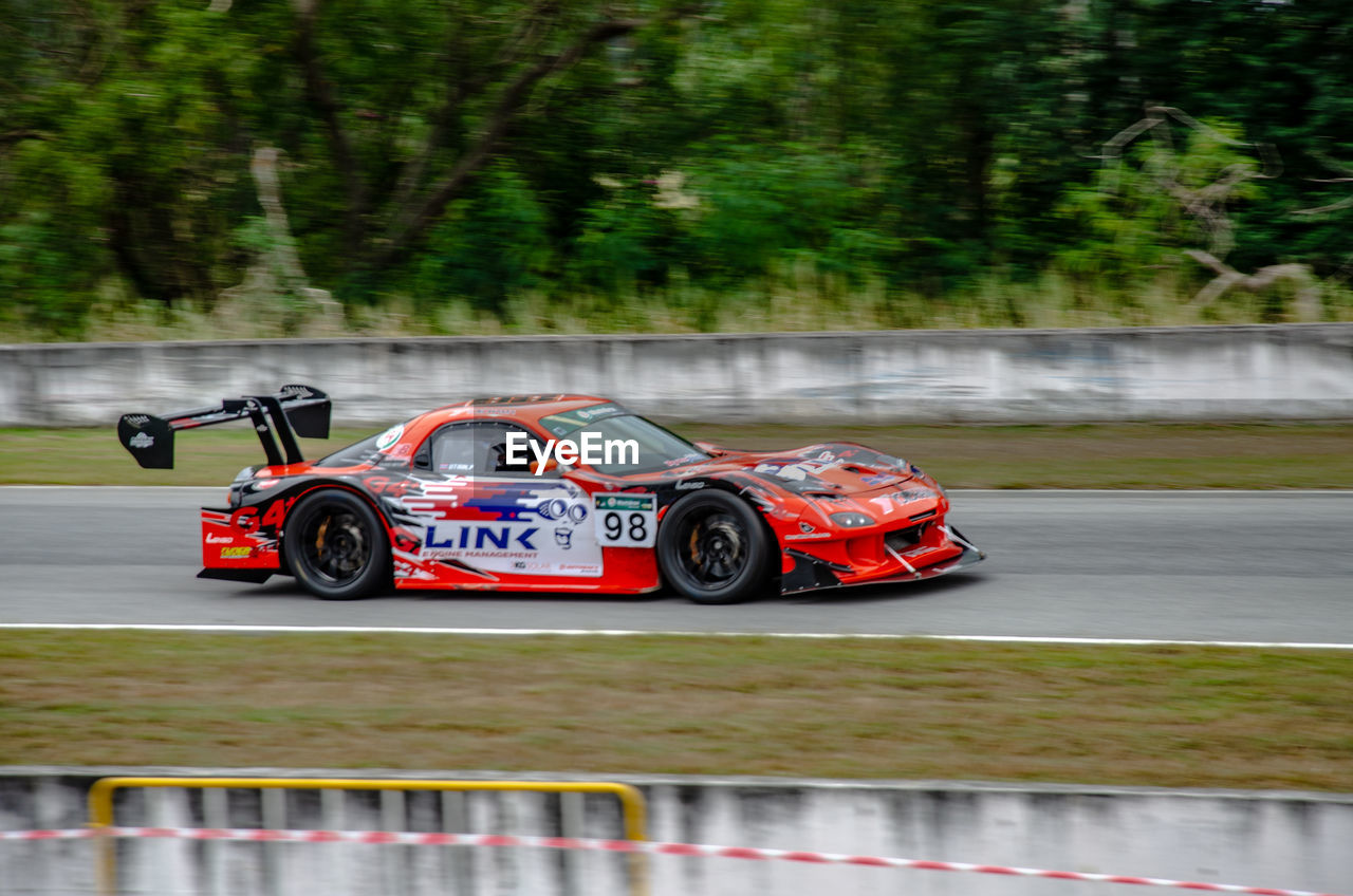 BLURRED MOTION OF CAR PARKED BY TREES