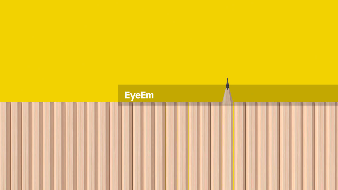 CLOSE-UP OF YELLOW PENCILS ON WALL