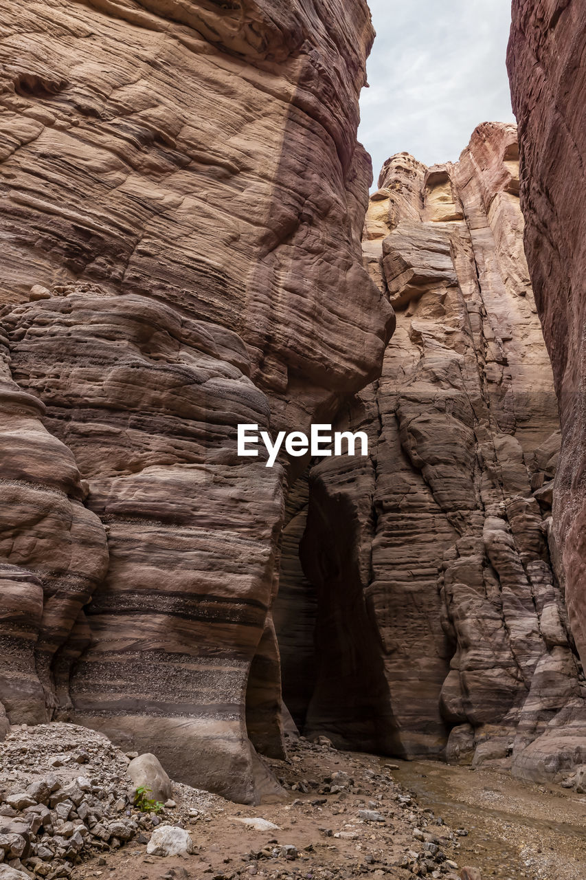 rock, rock formation, geology, arch, nature, travel destinations, non-urban scene, scenics - nature, no people, physical geography, beauty in nature, land, travel, eroded, landscape, environment, wadi, canyon, desert, sandstone, climate, tranquility, day, cliff, outdoors, sky, ancient history, extreme terrain, arid climate, terrain, architecture, formation, tourism, tranquil scene, valley, remote, natural arch, cloud, pattern, history