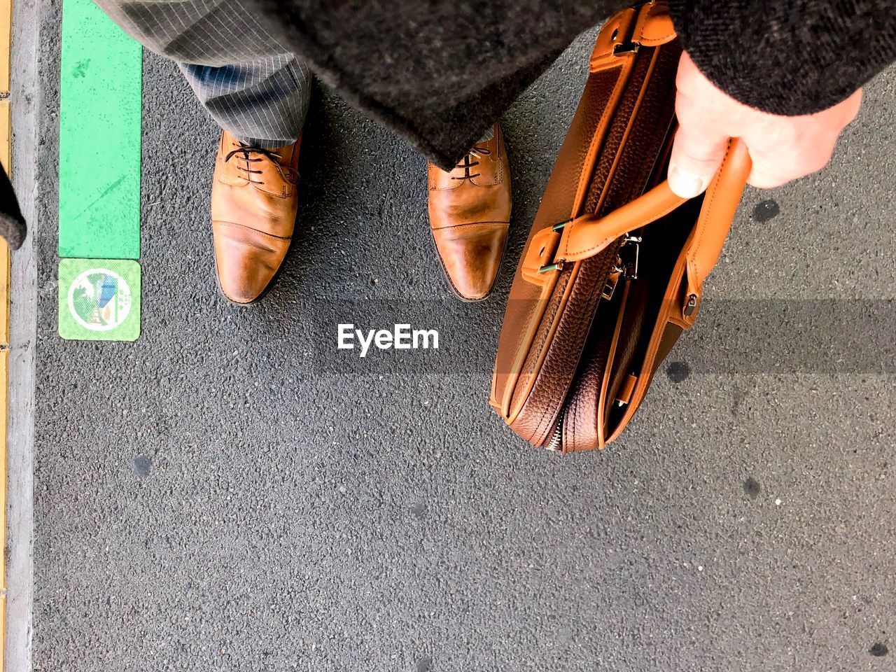 Low section of businessman holding suitcase standing on road