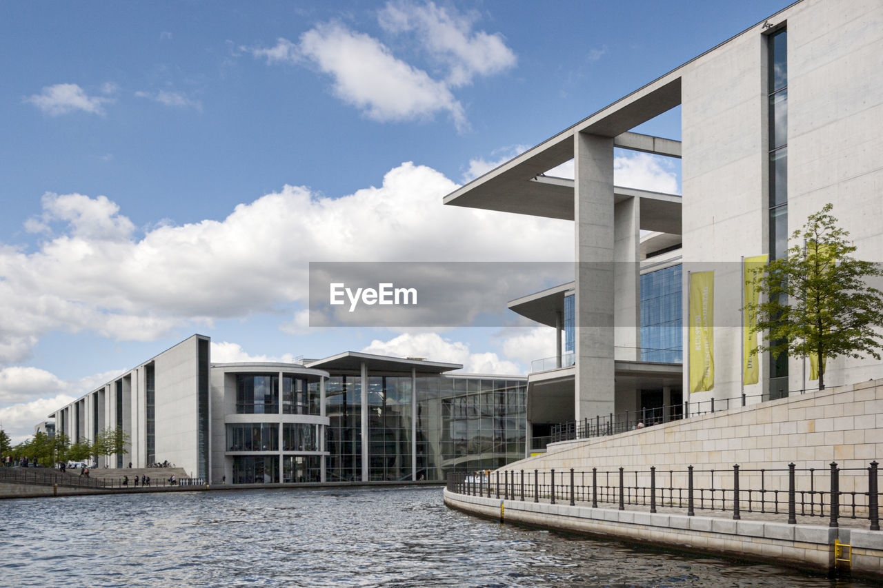 BRIDGE OVER RIVER AMIDST BUILDINGS AGAINST SKY