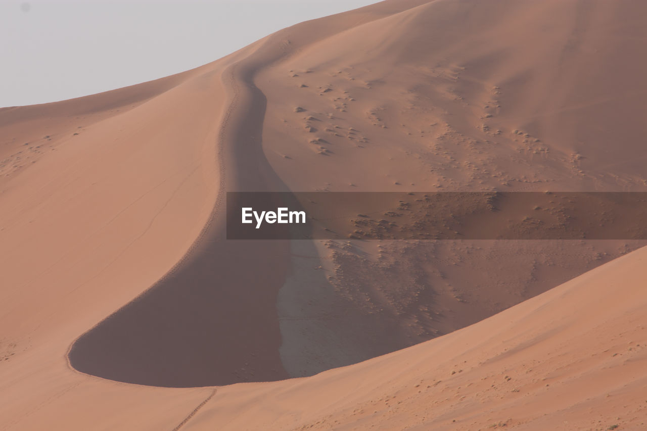 Sand dunes in desert against clear sky