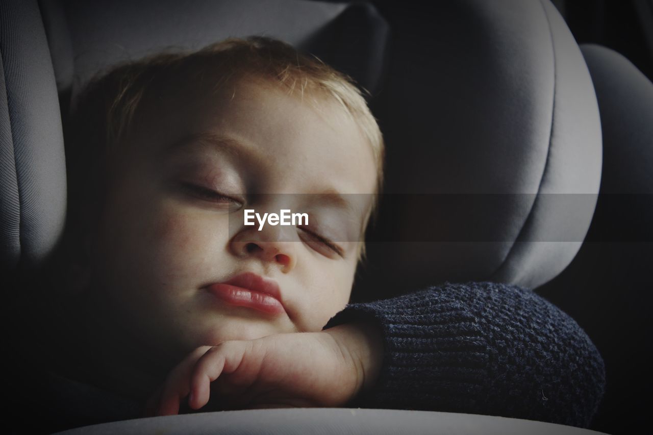 Close-up of cute baby boy sleeping on car seat