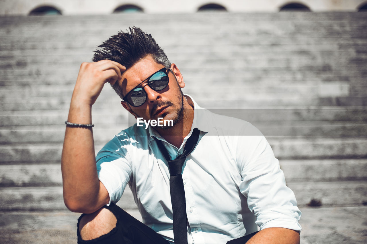 Portrait of man with hand in hair sitting on steps