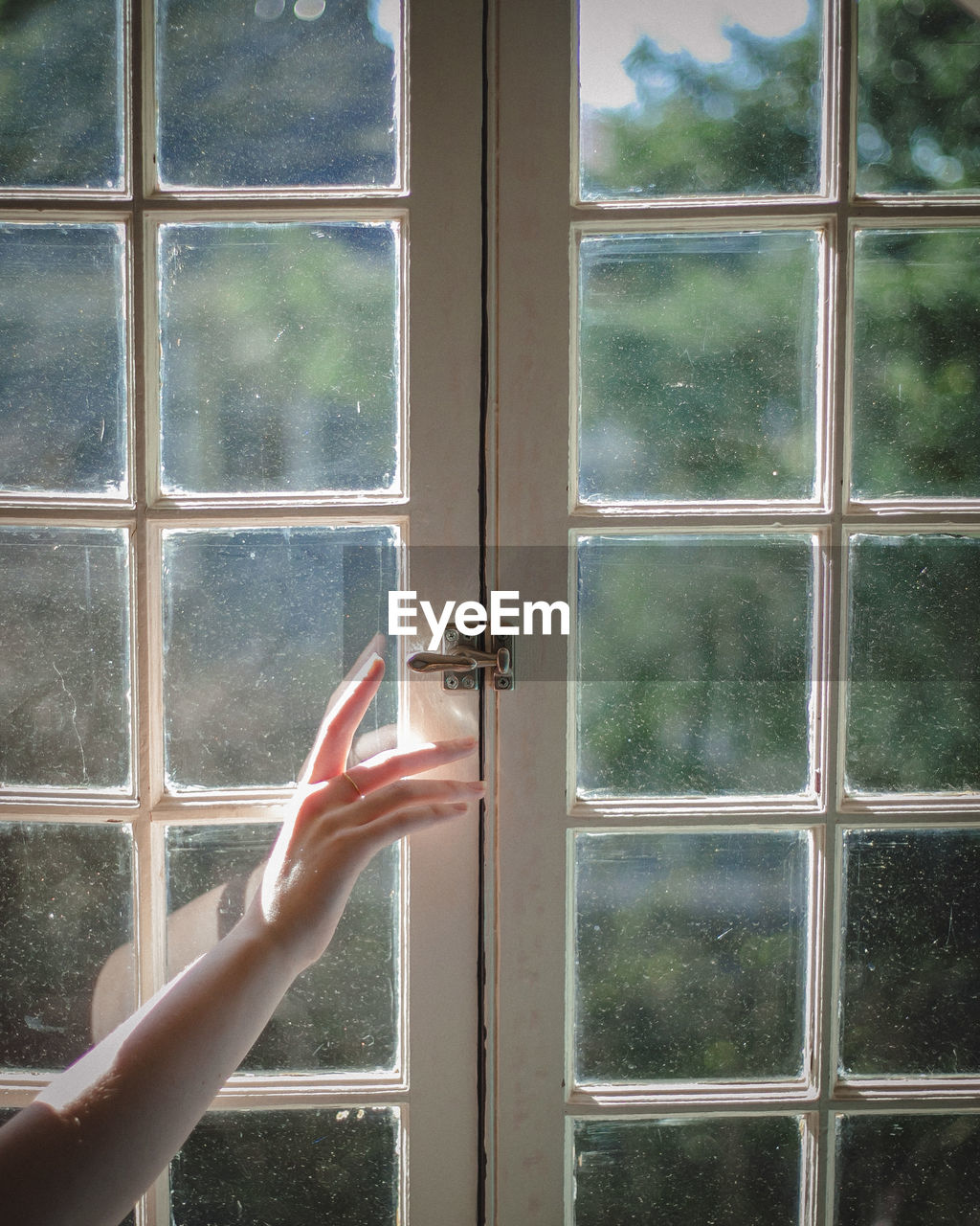 Cropped hand of woman opening window