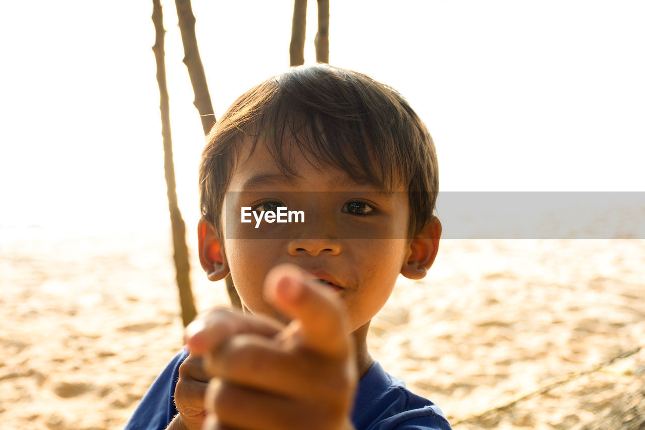 PORTRAIT OF BOY HOLDING SUNGLASSES ON LAND